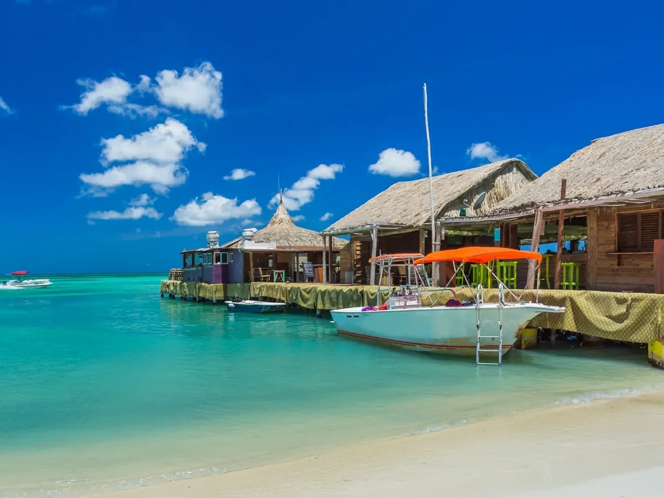 Thatched pier bars over a clear lagoon in Aruba
